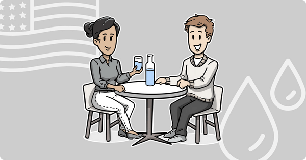 Two people sitting at a table drinking water.
